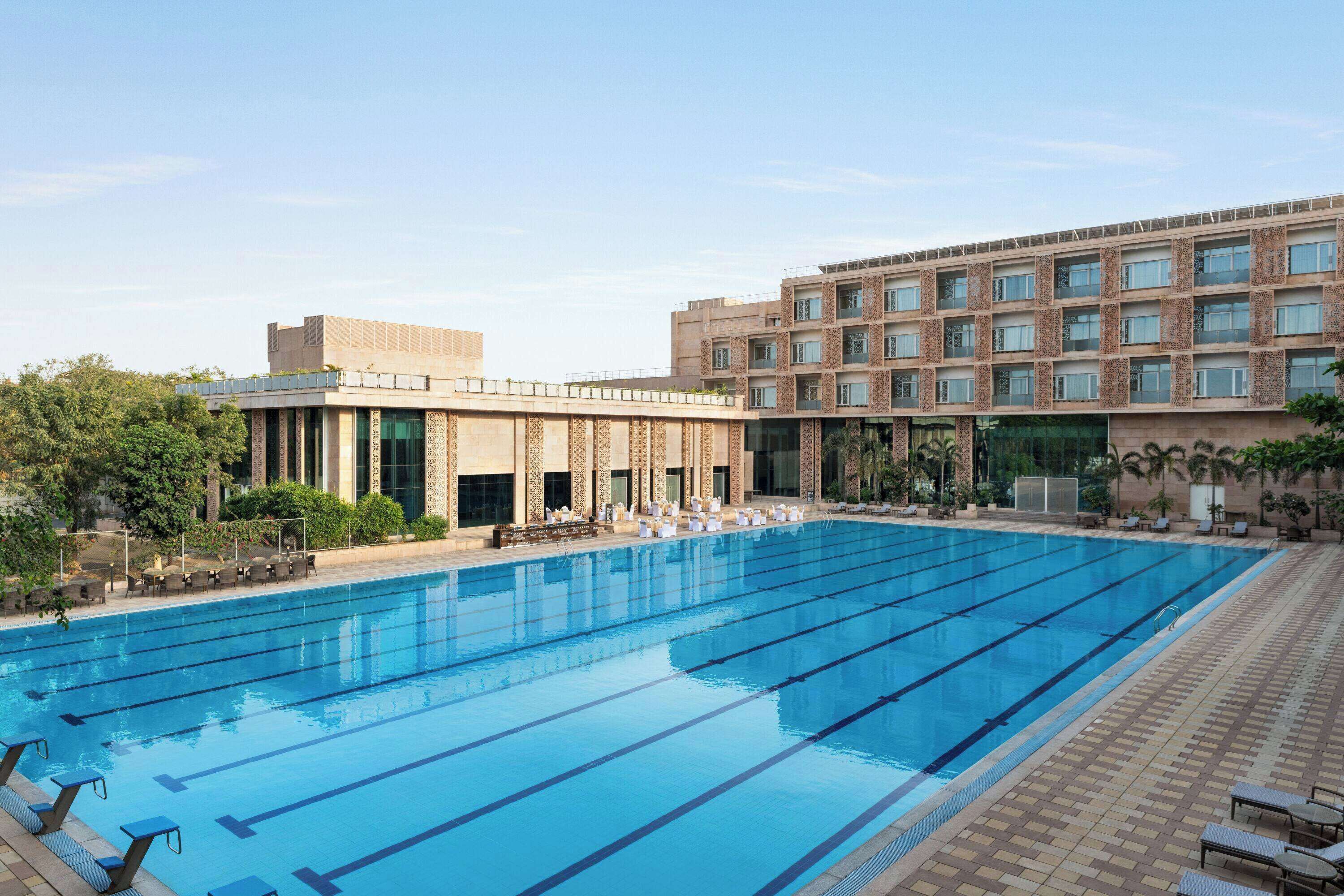 A swimming pool with multiple lanes, lounge chairs, and a building with a modern design.
