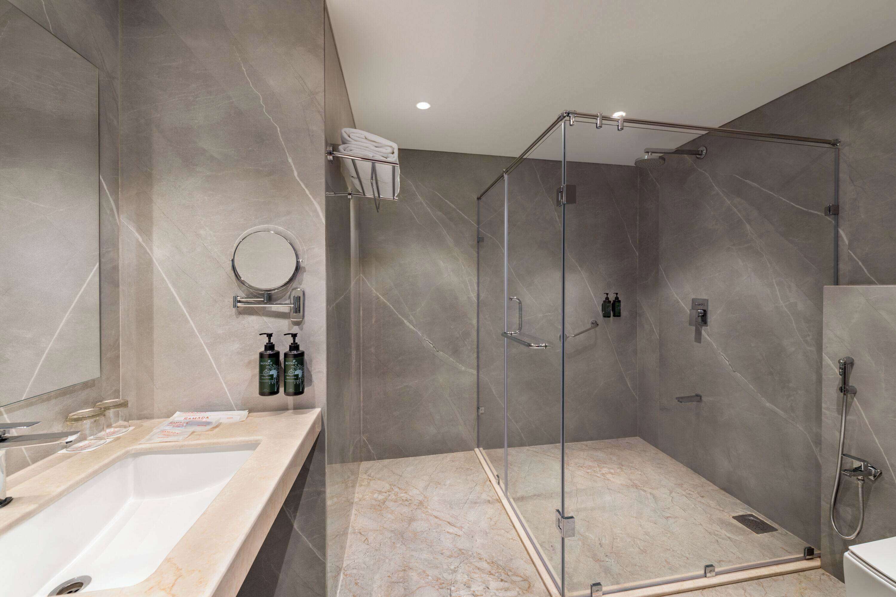 A modern bathroom with a large sink, a glass shower enclosure, and marble flooring.