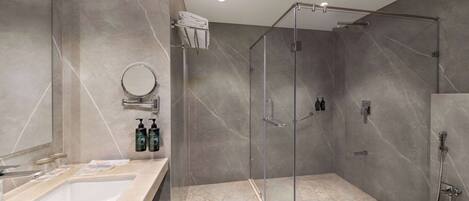 A modern bathroom with a large sink, a glass shower enclosure, and marble flooring.