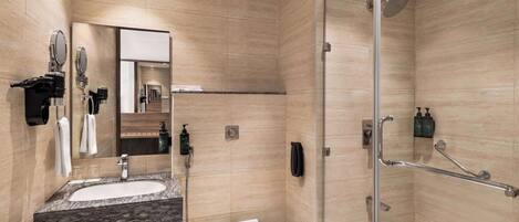 Une salle de bain moderne avec un lavabo en marbre, des toilettes, une douche en verre avec un pommeau de douche à main et un miroir à main.