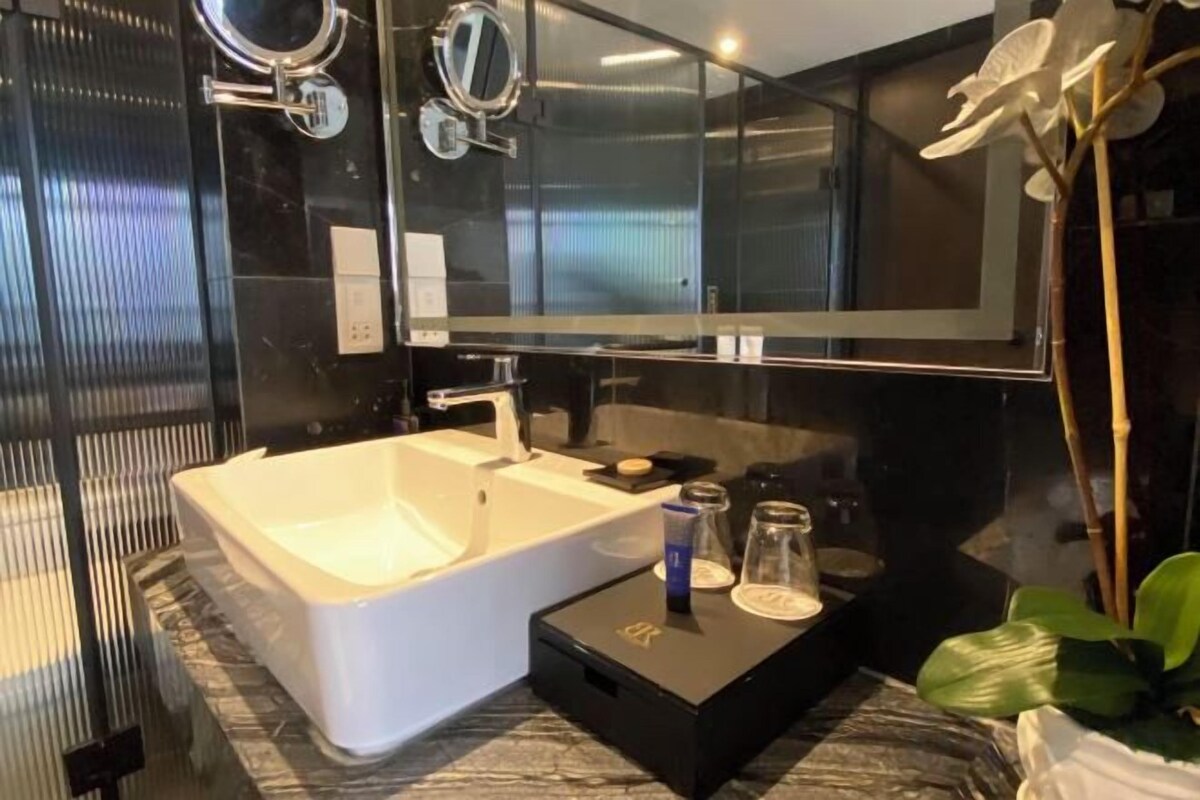 A modern bathroom with a large bathtub, a mirror above the sink, and a potted plant.