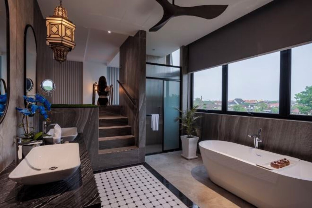 A modern bathroom with a large bathtub, a sink, and a staircase leading to a balcony.