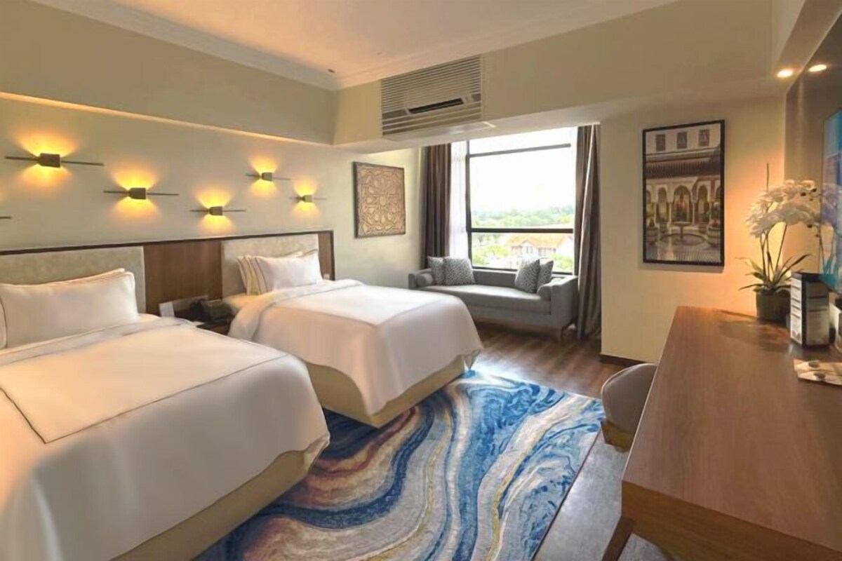 Ett hotellrum med två sängar, ett matbord, en soffa och ett stort fönster med utsikt.