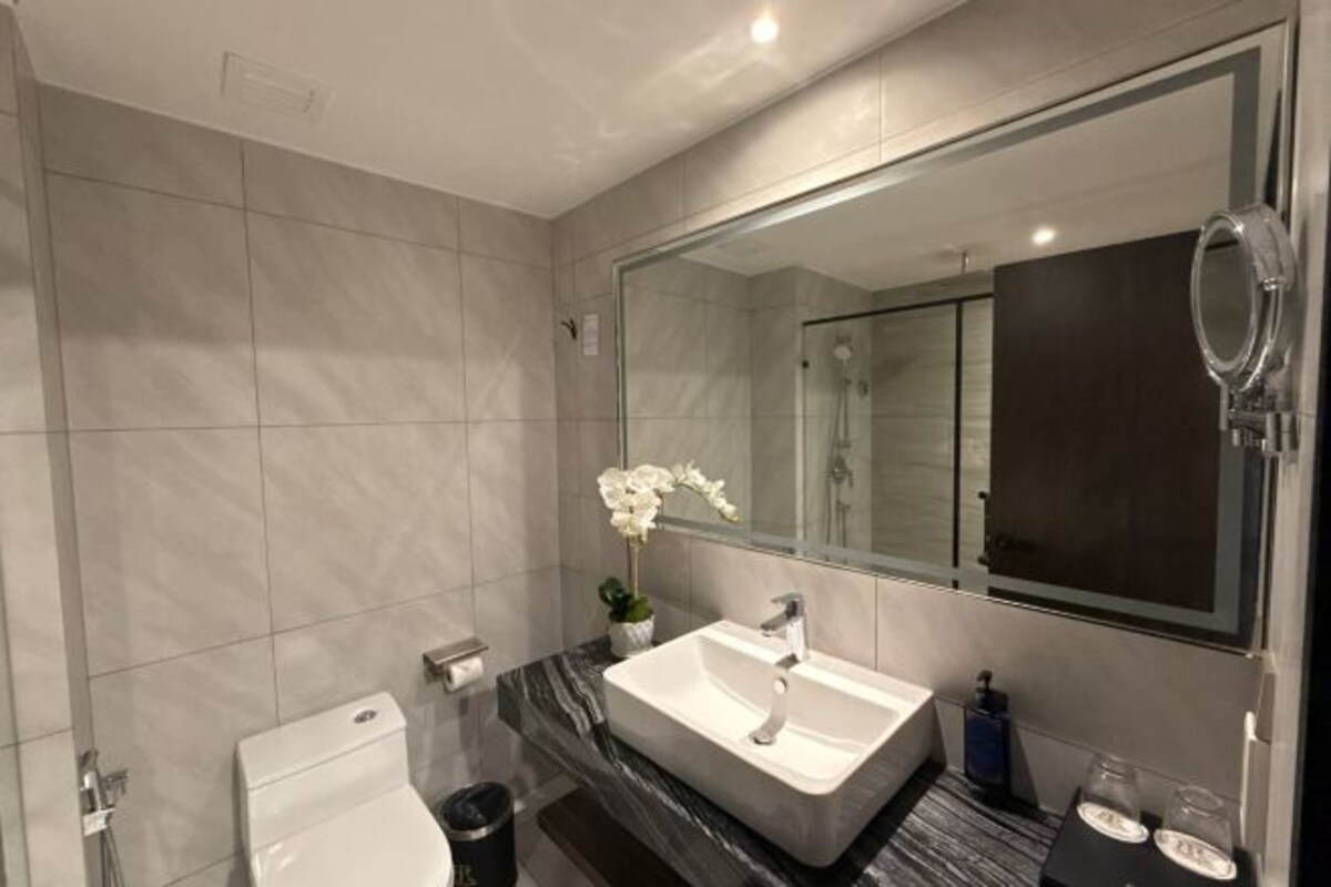 A modern bathroom with a large mirror, a white sink, and a toilet.