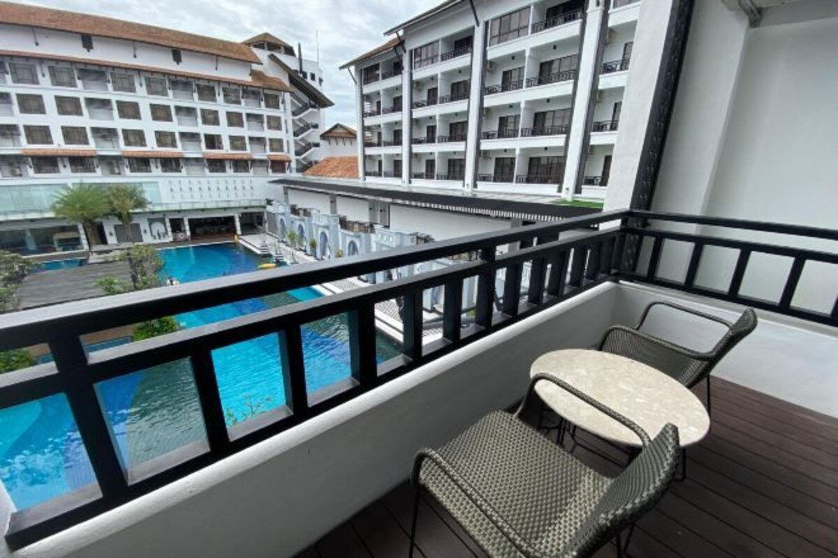 A balcony with a view of a swimming pool and adjacent buildings.