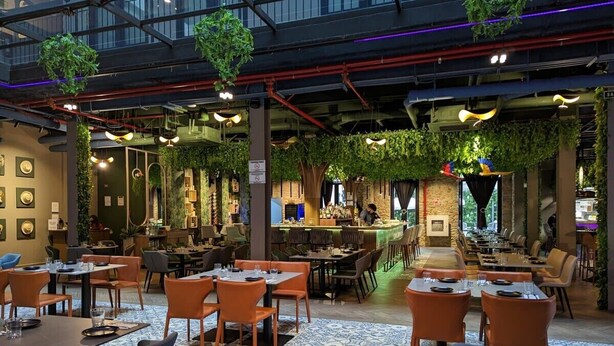 Un restaurant doté de plusieurs espaces de restauration, de plantes suspendues et d’un bar.