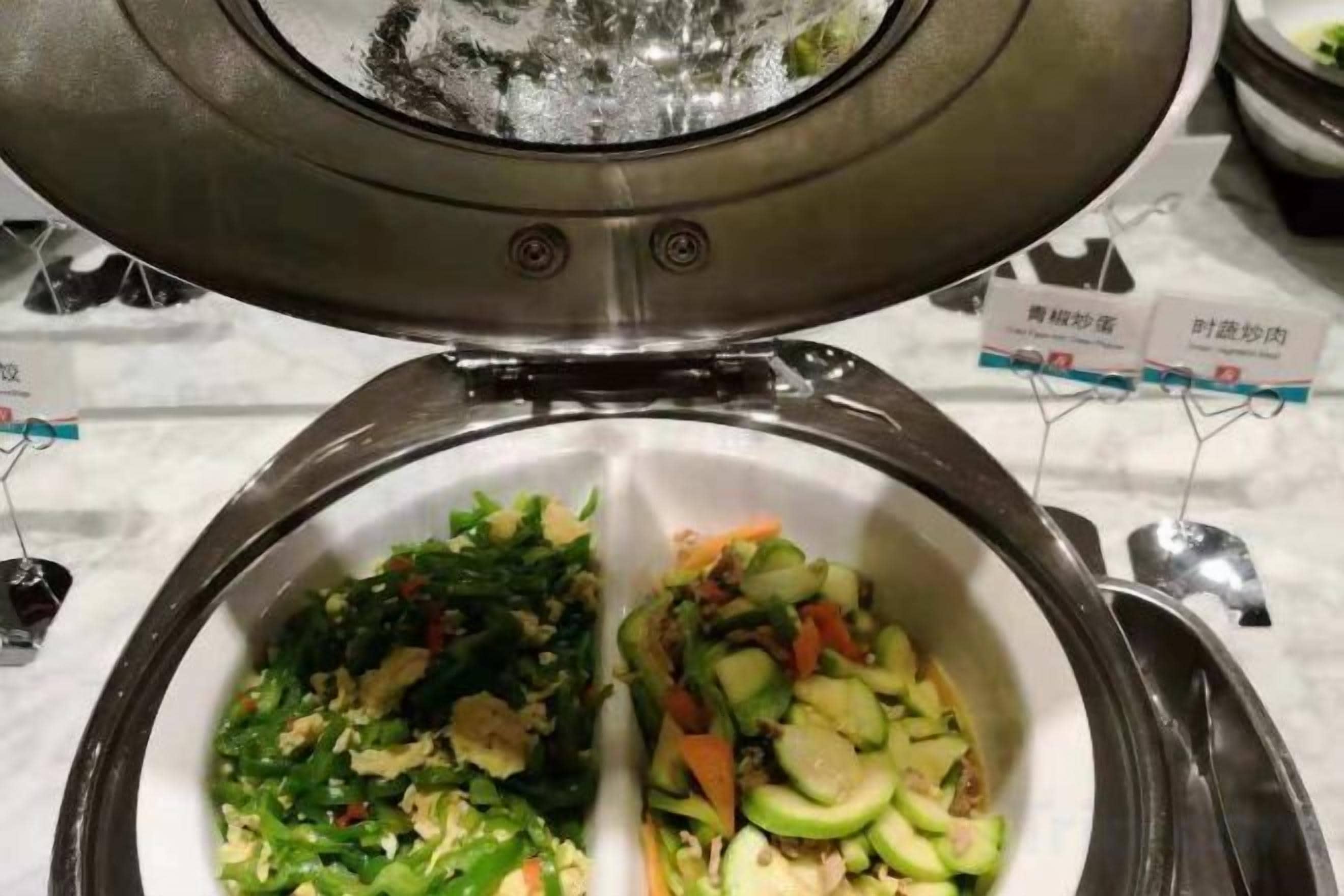 A buffet with two distinct sections of food, one with leafy greens and the other with vegetables.