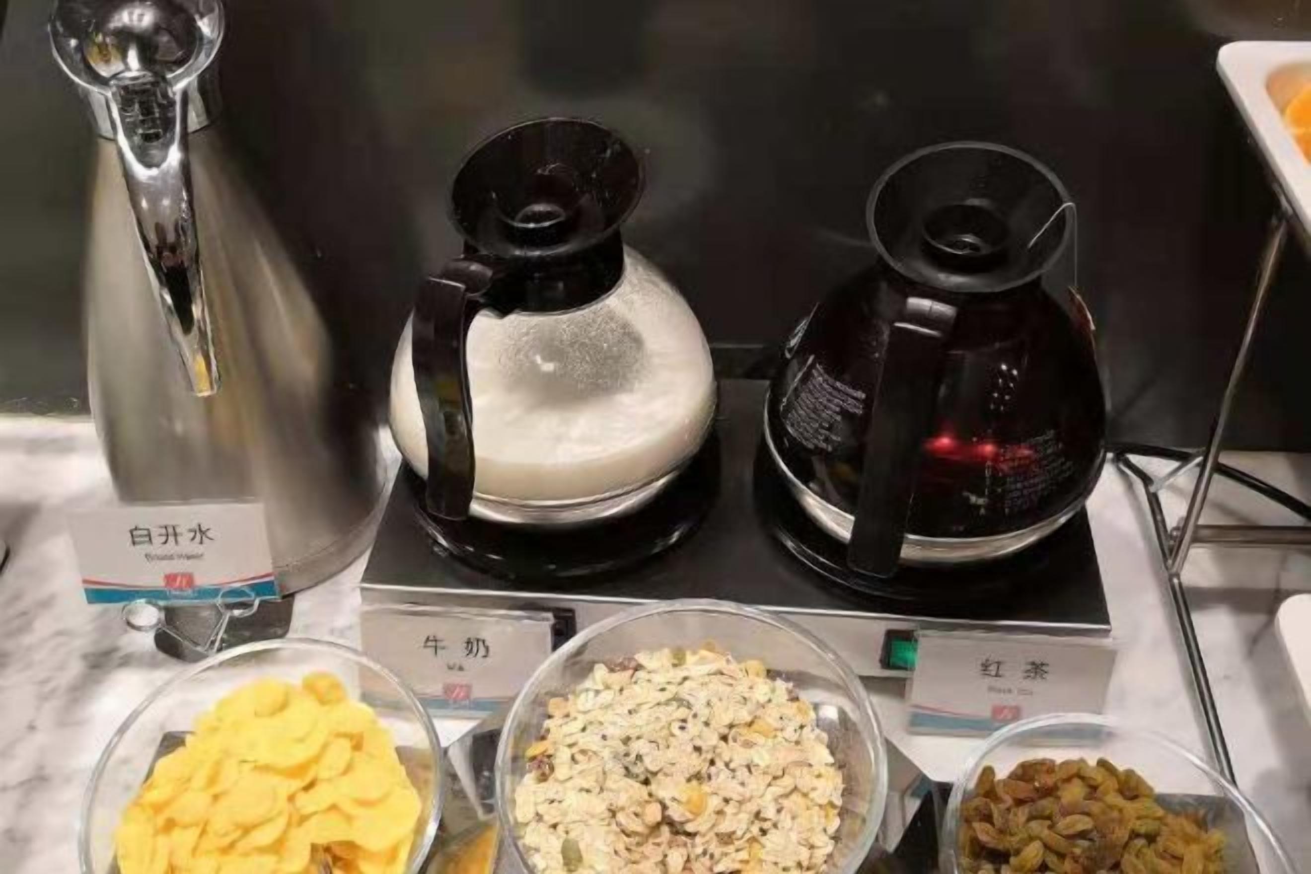 A coffee station with two coffee makers and three bowls of different food items.