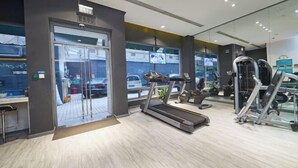 A modern gym with a treadmill, weight machines, and a large window overlooking a parking area. - Jinjiang Inn (Shanghai People's Square East Huaihai Road) (Shanghai)