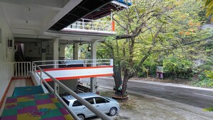Ein Hotel mit Balkon, einem geparkten Auto und Blick auf die Straße und Bäume.