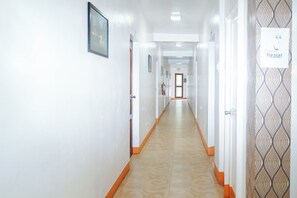A long, narrow hallway with white walls, orange trim, and patterned wallpaper on one side. - C Star Travellers Inn Redpartner (Oslob)