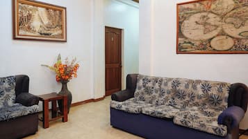 A room with two sofas, a wooden door, and a wall-mounted map.