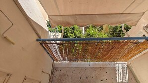 Un étroit couloir extérieur agrémenté d’un paravent en bambou, doté d’un sol carrelé et d’un ventilateur de plafond.
