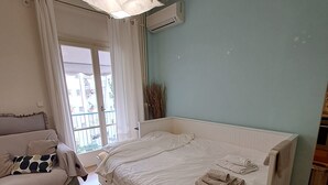 Une chambre à coucher avec un lit, une chaise, une table et une fenêtre avec des rideaux.