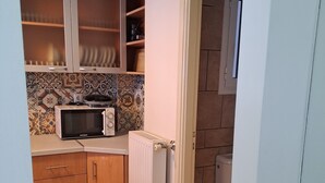 Une cuisine de taille réduite, équipée d’un four à micro-ondes, de meubles en bois et d’un pare-feu en carrelage.