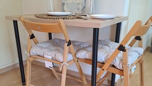 Une table à manger en bois, des chaises rembourrées, un vase rempli de fleurs et un tableau encadré accroché au mur.