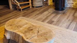 Un intérieur rustique avec un escalier en bois, un poêle à bois et une grande table en bois.