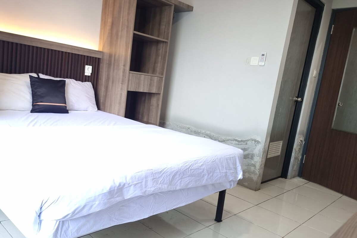 A hotel room with a bed, a wooden headboard, a wardrobe, and a door.