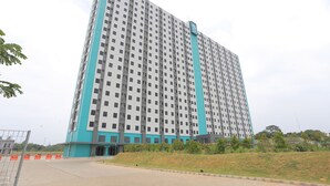 A high-rise building with a uniform facade, multiple balconies, and a central entrance.