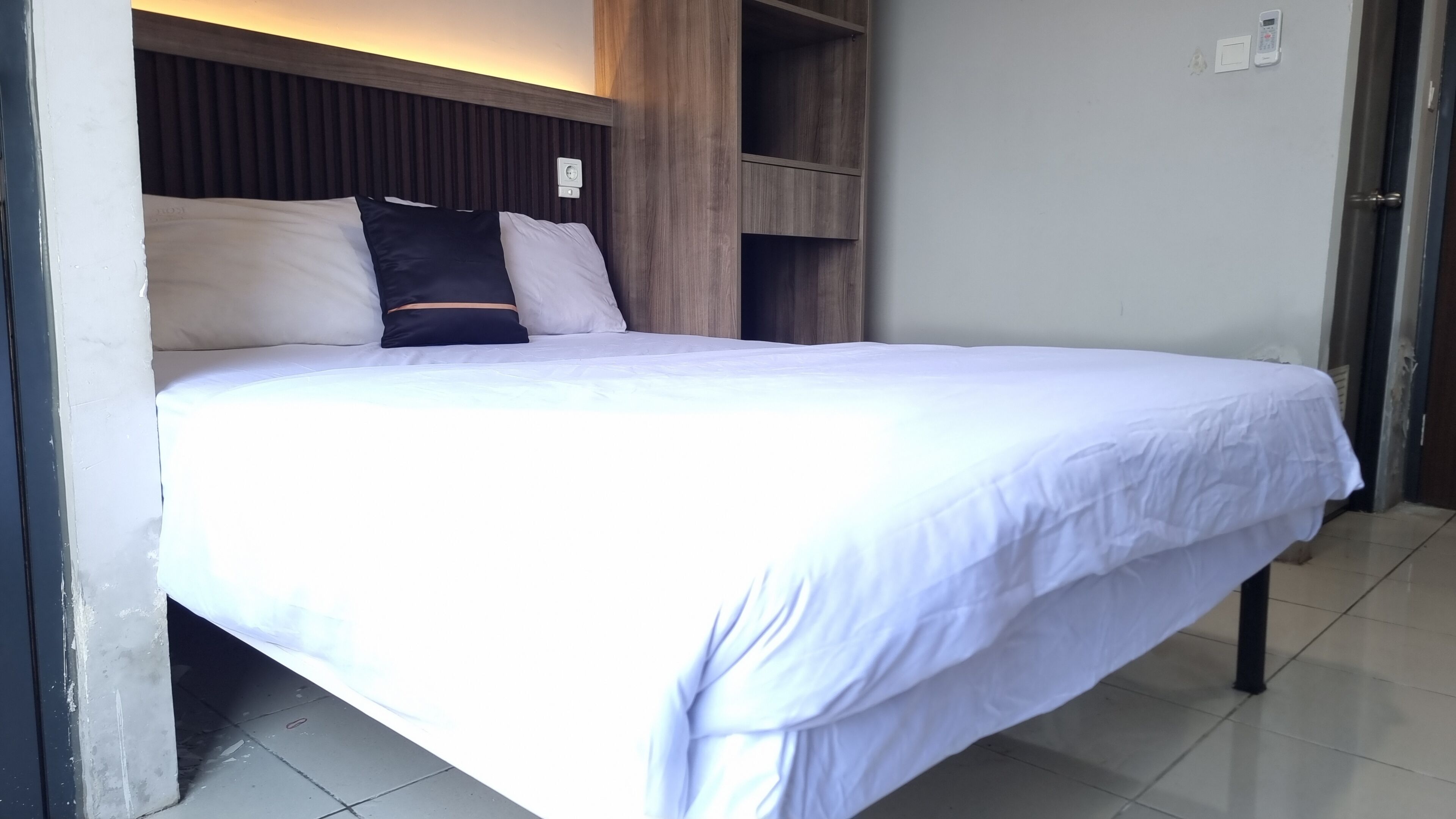 A neatly made bed with white bedding and a wooden headboard.