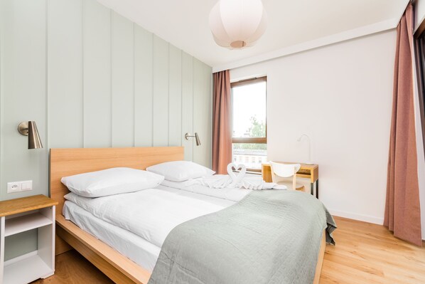 A neatly made bed with white linens, a wooden headboard, and a bedside table with a lamp.