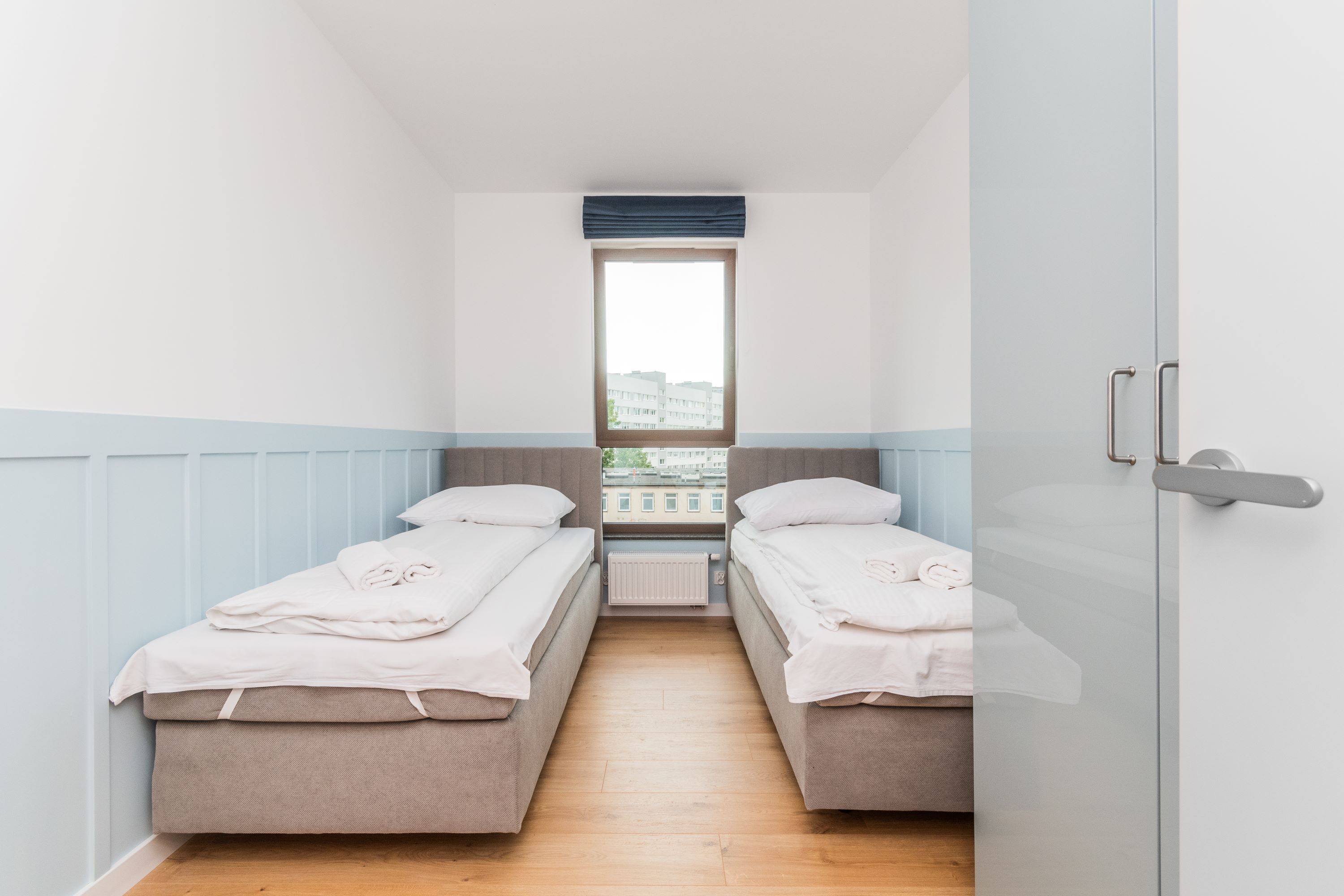 A room with two beds, a window, and a radiator.