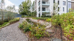 A residential building with balconies, a garden with a pond, and a cobblestone path. - Bulvar Premium by Grand Apartments (Gdansk)