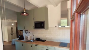 A modern kitchen with light green cabinets, a stainless steel microwave, and a wooden countertop. - Rincón de Piedra a 30' de Barcelona (Corró d'Avall)