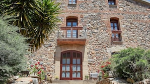 A stone building with a central entrance, steps leading up to it, and a balcony with railings. - Rincón de Piedra a 30' de Barcelona (Corró d'Avall)