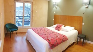 A bedroom with a bed, a chair, a window, and a wall-mounted lamp. - Un Appart Dans le Perche, Votre Pied à Terre ! (Nogent-le-Rotrou)