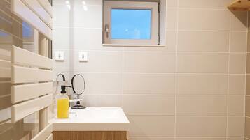 Ein modernes Badezimmer mit einem weißen Waschbecken, einem Holzkabinet und einem kleinen Fenster über dem Spiegel.
