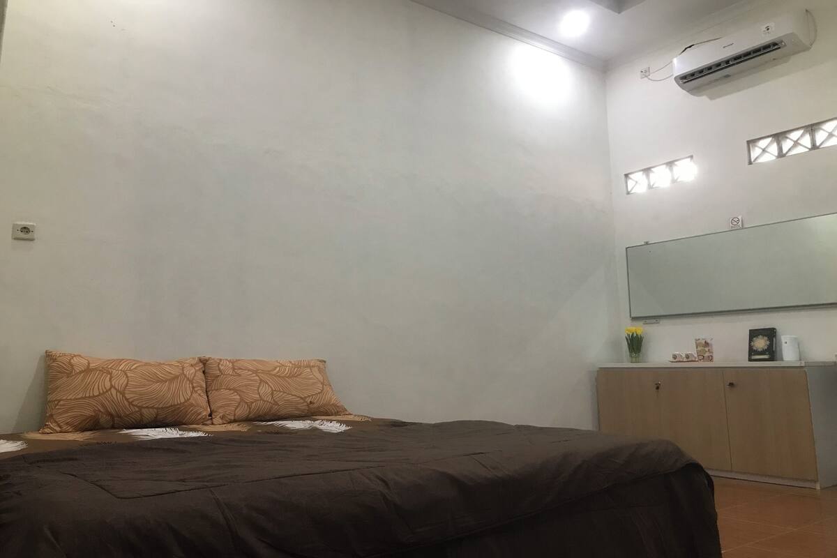 Ein Schlafzimmer mit Bett, Kleiderschrank, Spiegel und einer Klimaanlage.