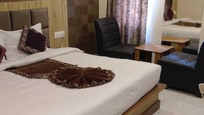 A hotel room with a large bed, a headboard, an air conditioning unit, a chair, a small table, and a mirror. - Hotel Glass INN (Dera Bassi)
