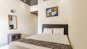 A hotel room with a large bed, a bedside table, a mirror, and a wall clock. - OYO 94152 Pondok Wisata Alan Dinah (Seririt)