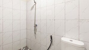 A bathroom with white marble tiles, a shower with a handheld showerhead, and a toilet with a white tank. - OYO 94152 Pondok Wisata Alan Dinah (Seririt)