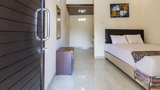 A hotel room with a bed, a small cabinet, a mirror, and a wall art piece. - OYO 94152 Pondok Wisata Alan Dinah (Seririt)