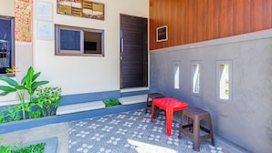 A small, enclosed outdoor area with a red table and two stools, a door, and a window. - OYO 94152 Pondok Wisata Alan Dinah (Seririt)