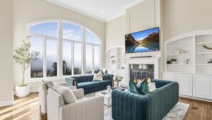 A spacious living room with a fireplace, large windows, and a television. - Grand Villa Castle in San Jose (San Jose)