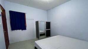 A small, clean room with a single bed, a wardrobe, and a blue curtain. - Hotel O Kost Btnompo Near SDI Bontosallang (Bontonompo)