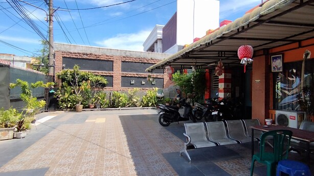 Un bâtiment doté d’un patio carrelé, d’une rangée de chaises et d’une moto garée à l’extérieur.