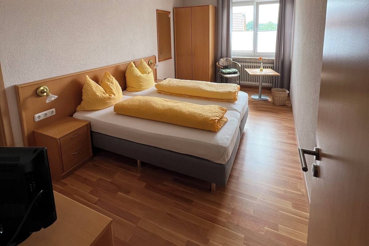 Een moderne hotelkamer met een groot bed, een houten hoofdeinde en een klein nachtkastje.