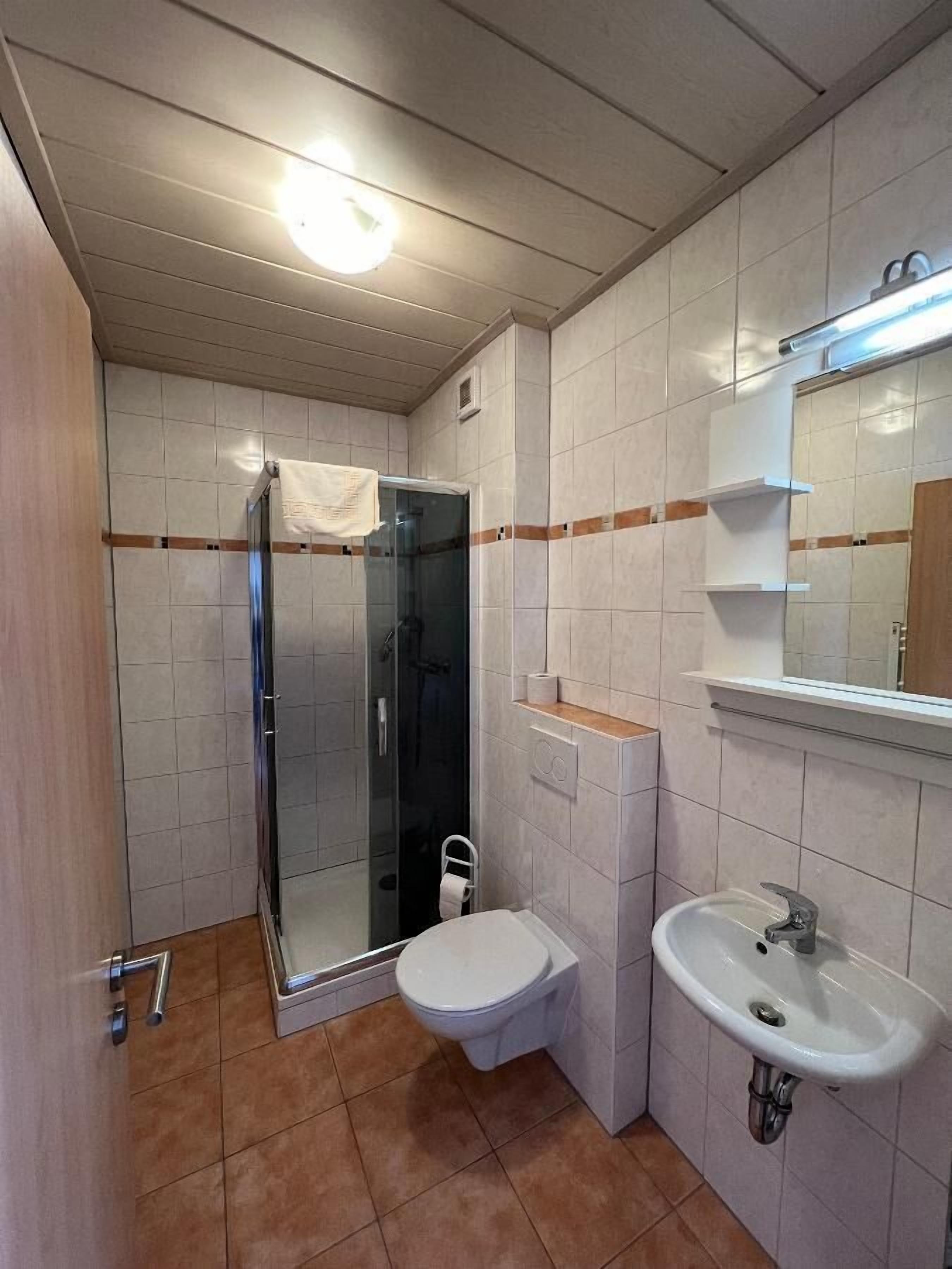 Un baño con cabina de ducha de vidrio, inodoro, lavabo y espejo.