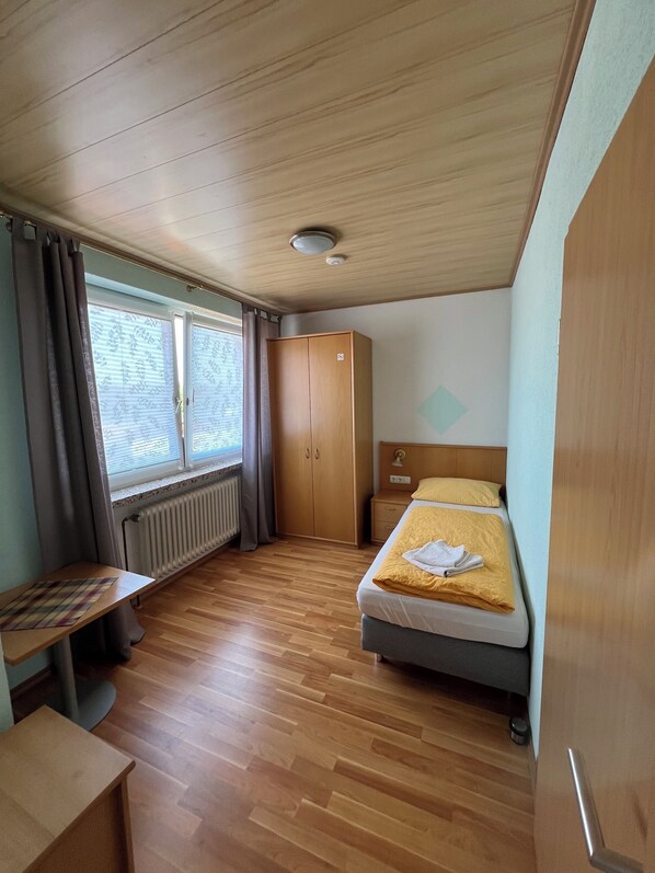 A compact room with a bed, a desk, and a wardrobe. - Gasthaus & Metzgerei Besenhardt (Wackersdorf)