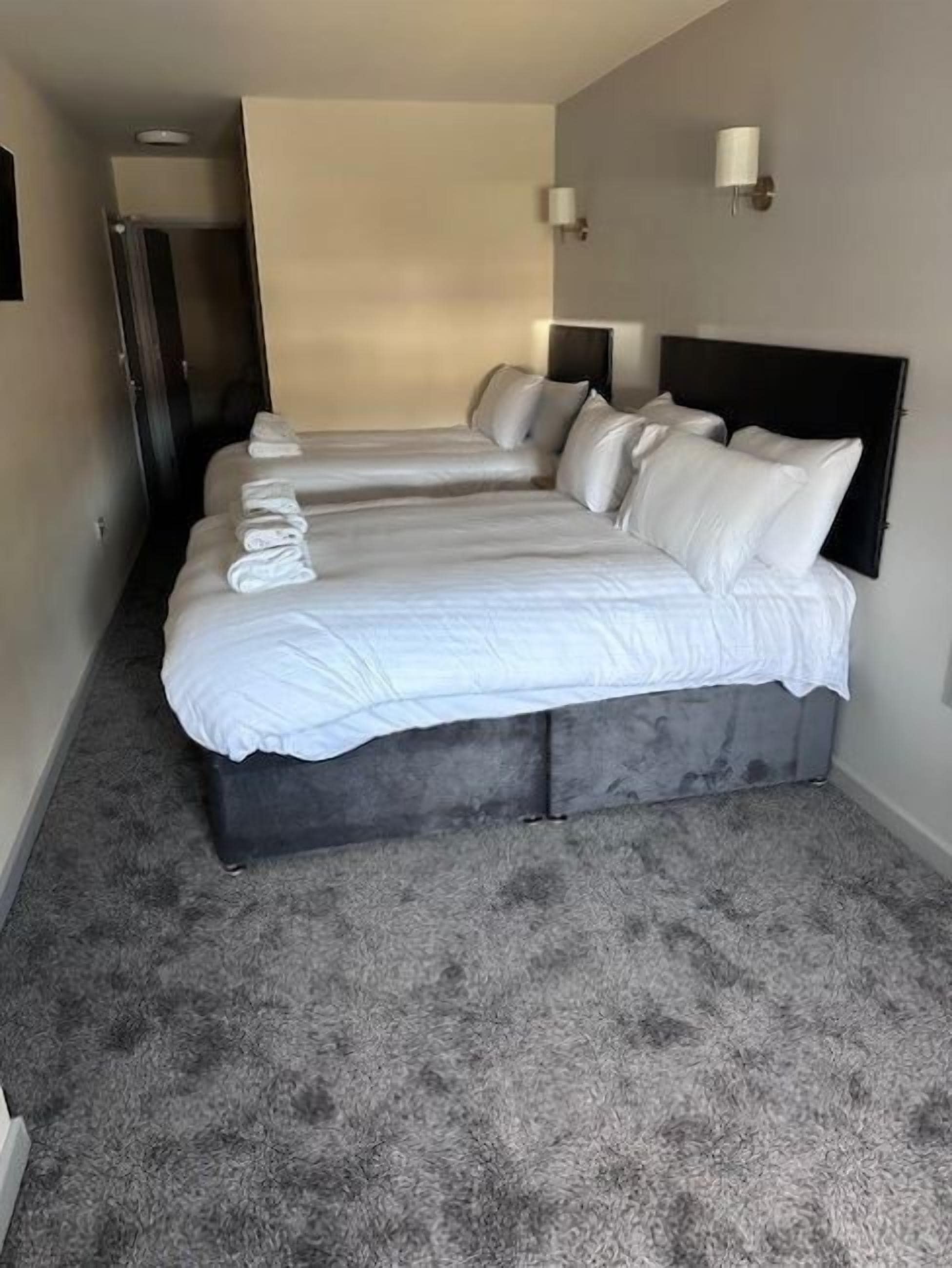 A hotel room with two beds, grey carpet, and a modern design.