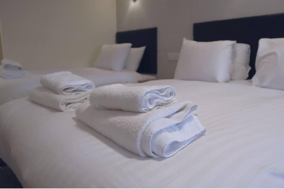 A hotel room with two beds, each with neatly folded white towels and matching pillows.