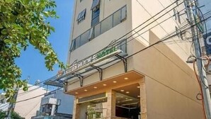 A multi-story hotel with a prominent entrance and a staircase leading to the lobby. - Lotus Rock Hotel DN by Bay Luxury (Da Nang)