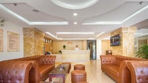 A lobby with leather sofas, a reception desk, and a TV screen. - Lotus Rock Hotel DN by Bay Luxury (Da Nang)