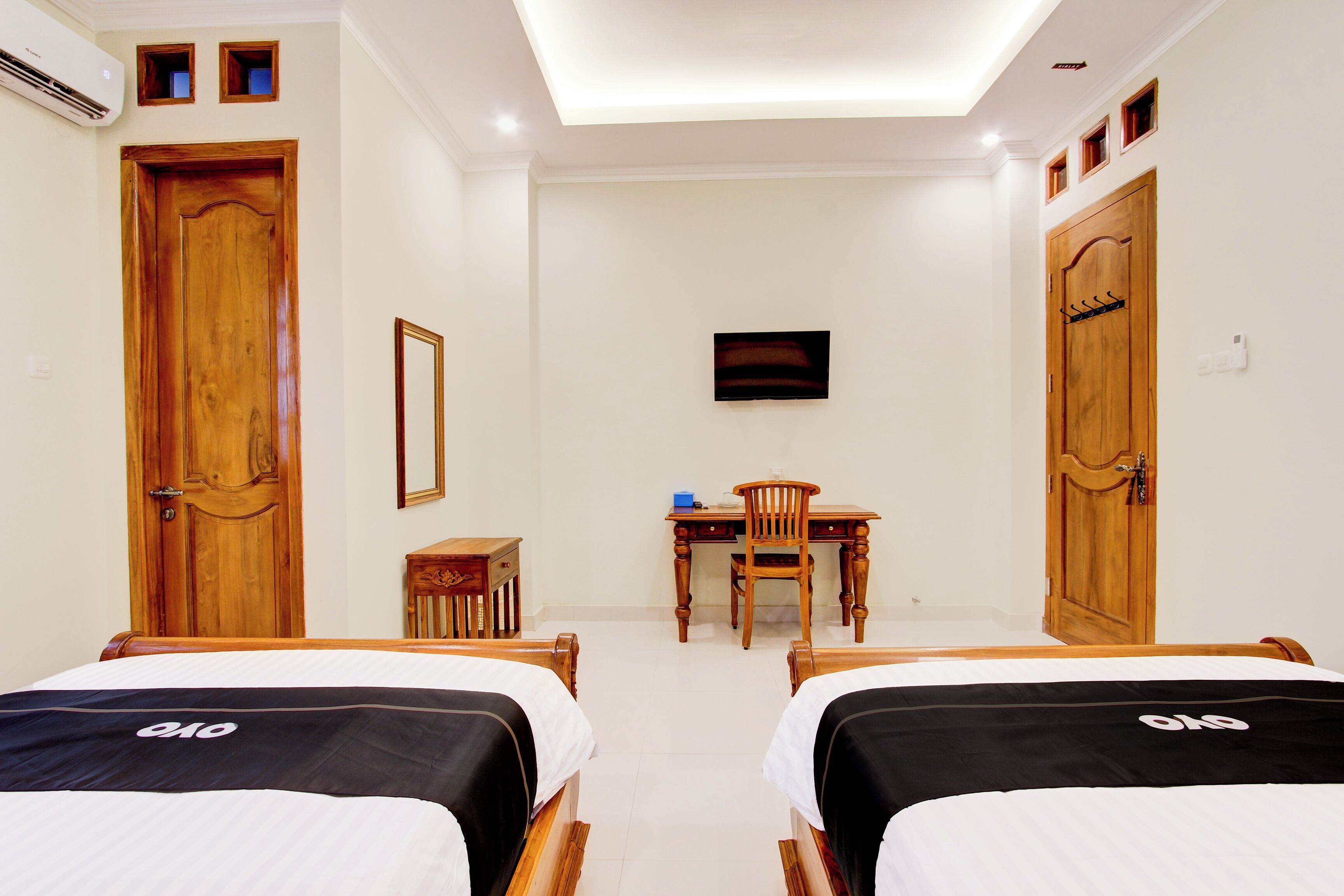 A hotel room with two beds, a desk, a chair, and a television.