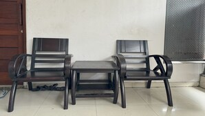 A corner seating area with two chairs and a small table, a wooden door, and a metal gate. - Hotel O Kost Aisyah Near Citra Grand Galesong City(Pattalassang) (Pattallassang)