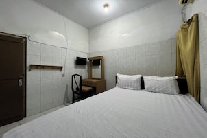 Quarto com cama, cadeira, escrivaninha, televisão e guarda-roupa.